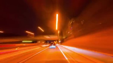 Gece şehirde hızlı bir araba yolculuğu sokak ışıklarının altında, uzun süre. Işıkların ve neon ışıkların yansıması, arabanın ön camında. Tema şehir ve gece hayatına hızlı bir şekilde taşınan otomobil.