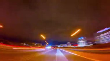 Akşamları gece trafik ışıklarında uzun süreli hızlı araba görüntüsü. Şehir merkezinde şehir hayatı, otoyoldaki şehir ışıkları, yol ulaşımı. Gecenin ilerleyen saatlerinde yüksek yolda seyahat et..