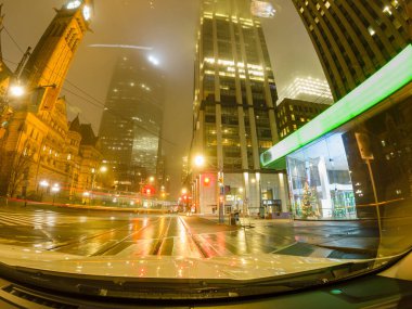 Long exposure pov of car driving through city of Toronto downtown. Ontario, Canada. Travel trip, dash cam or car camera view forward at night rainy city. clipart