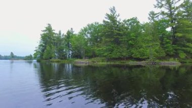 Kanada Gölü 'nün kayalık ladin kıyı şeridinin POV görüntüsü. Küçük taç köknar ağacı adaları kıyısı. Güneşli bir günde bulutlu bir havada motorlu tekne. Seyahat ve macera.