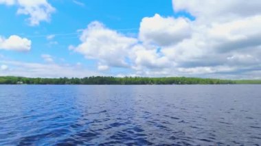 Köknar ağaçları ve bitki örtüsü arasındaki tatlı su gölünde kayıkla gezen küçük tekneden POV. Balıkçılık sırasında hareket eden tekne önü trollerinin görüntüsü. Güzel Kuzey Amerika rüya manzarası.