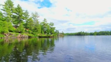 Köknar ağaçları ve bitki örtüsü arasındaki tatlı su gölünde kayıkla gezen küçük tekneden POV. Balıkçılık sırasında hareket eden tekne önü trollerinin görüntüsü. Güzel Kuzey Amerika rüya manzarası.