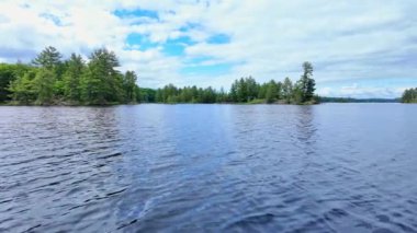Güzel köknar ağaçları ve teknede balık avlarken gölün kayalık kıyı şeridi manzarası. Hobilerin yaşam tarzı balıkçılık. Eğlence amaçlı balık tutma sporu. Şaşırtıcı Kuzey Amerika doğası.