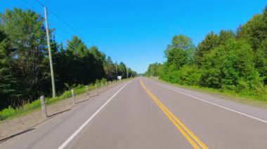 28. otoban kayalık yeşillikten geçiyor. Uzun yeşil ormanlar boyunca asfalt yol. Arabanın arka kısmından sürüş plakası: Bancroft, Kawartha, Ontario, Kanada - 28 Haziran 2024