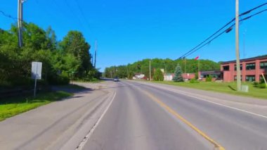 28. otoyol boyunca küçük bir kasabanın arka geniş görüş alanı var. Oradan geçen ev ve iş yerleri. Arabanın arkasından asfalt yol manzarası: Bancroft, Kawartha, Ontario, Kanada - 28 Haziran 2024