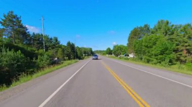 28. otobanın geniş açılı çekim plakalı kamera pov 'u Kanada kalkanının yeşillik bolluğunu geçiyor. Arabanın arkasından asfalt yol manzarası: Bancroft, Kawartha, Ontario, Kanada - 28 Haziran 2024