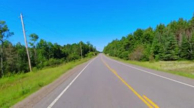 28. otobanın geniş açılı çekim plakalı kamera pov 'u Kanada kalkanının yeşillik bolluğunu geçiyor. Arabanın arkasından asfalt yol manzarası: Bancroft, Kawartha, Ontario, Kanada - 28 Haziran 2024