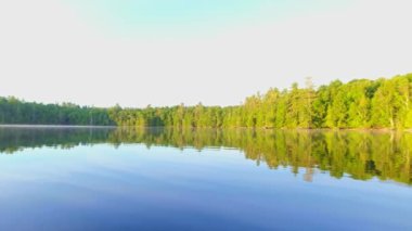 Muhteşem gün doğumu güneş ışığı etrafını çevreleyen köknar ormanına sızıyor. Kuzey Amerika 'daki güzel göl manzarası. Sessiz Göl 'de Kanada doğasının tatil köyü, balık avı ve dinlendirici çevre.
