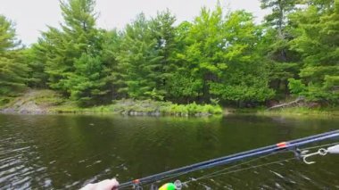 Angler sabahın erken saatlerinde şişme botta trollerken koca ağızlı levrekler için yapay balık yemi ile döküm çubuğu hazırlıyor. Balıkçının el ele tutuşması.