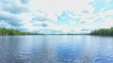 Köknar ağaçlı küçük gölün tekne pruvasından POV manzarası. Kuzey Ontario Gölü 'ndeki kır sularında tekne gezisi. Çam ağaçlı yeşil orman gölü. Küçük göl bitkilerinin panoramik manzarası.