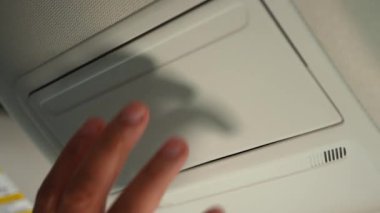 Kadın sürücü arabanın tavan kapağını açıyor ve içinden gözlük çıkarıyor. Arabanın tavanındaki gözlük kutusu açık ve kullanılıyor. Kapat..