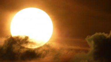 Apokaliptik sinematik büyük güneş, kara bulutların ardında batıyor. Karanlık kıyamet bulutlarının arasından geçen göz kamaştırıcı sıcak günbatımı güneşi zaman atlaması. Yargı günü ruh hali ve atmosferi.