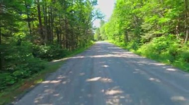 Motokros yarışçısı plaka kullanıyor, engebeli off-road 'a biniyor, dağlarda hızlı sürüş yapıyor, aşırı maceralar yaşıyor. Arka plan Sürücü Plakası Kırsal yolda geriye doğru bakıyor.