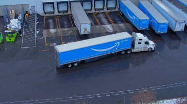 Amazon freight truck near warehouse with symbol blue logo of a company. Amazon delivery vehicle in the city. Multinational e-commerce company: Agincourt North, On, Canada - December 7, 2023. clipart