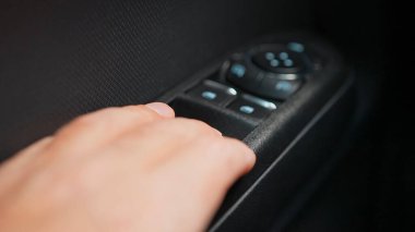 Sürücü arabanın kapısının kolundaki pencereyi açar ve kapatır. Araba kapısı pencerelerini açmak ve kapatmak için elektrik mekanizması düğmesi.