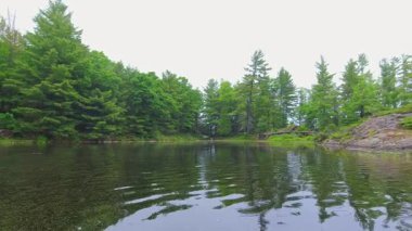 Suyun içinden geçen bir gemiden Pov. Kanada Gölü 'nde tekne manzarası, küçük teknenin pruvasında. Küçük taç köknar ağacı adaları kıyısı. Güneşli bir günde bulutlu bir havada motorlu tekne. Seyahat ve macera.