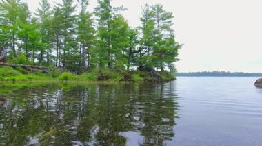 Suyun içinden geçen bir gemiden Pov. Kanada Gölü 'nde tekne manzarası, küçük teknenin pruvasında. Küçük taç köknar ağacı adaları kıyısı. Güneşli bir günde bulutlu bir havada motorlu tekne. Seyahat ve macera.