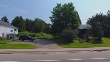 Pickerel Gölü 'nün Ontario kentindeki Burk' s Falls kasabasında, kırsal kesimde evleri olan geniş açılı asfalt yol manzaralı araba aracı: Burk 's Falls, Ontario, Kanada - 15 Temmuz 2024