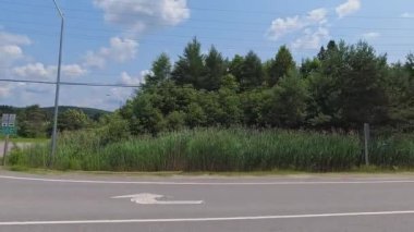 11. otoyola dönmenin yan görüntüsü, yol kenarlarında yeşillik. Arabayla manzara gezisi, sürücü bakış açısı POV. Burk 's Falls, Ontario, Kanada - 15 Temmuz 2024