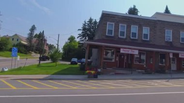 Pickerel Gölü 'nün Ontario kentindeki Burk' s Falls kasabasında, kırsal kesimde evleri olan geniş açılı asfalt yol manzaralı araba aracı: Burk 's Falls, Ontario, Kanada - 15 Temmuz 2024