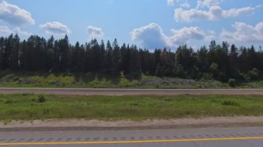 Sürücü plakası, doğal güzellik ve macera sergiliyor. Burk Şelalesi 'nin yakınındaki yol ve vahşi doğa geçidi boyunca birinci şahıs manzarası. Yol Yolculuğu: Parry Sound Highway 11, Ontario, Kanada - 15 Temmuz 2024