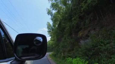 Araba yan aynası sürücü plakası. Yaz yolculuğunda aracın dikiz aynasına bak. Yeşil ağaçlar ve bitkilerle dolu kır evi otobanı manzarası. Otomobil hareket halinde.