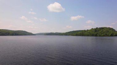 Yeşil orman ve tatil kulübeleriyle çevrili Baptist Gölü 'nün alçak drone manzarası, Kanada' da dağınık bulutlu mavi gökyüzü. Bancroft yakınlarında Kuzey Ontario 'nun temiz suları.
