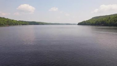 Yeşil orman ve tatil kulübeleriyle çevrili Baptist Gölü 'nün alçak drone manzarası, Kanada' da dağınık bulutlu mavi gökyüzü. Bancroft yakınlarında Kuzey Ontario 'nun temiz suları.