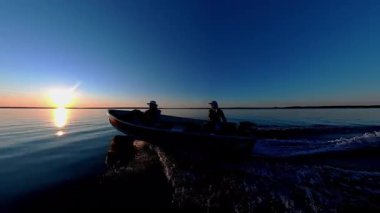 Akşam Huron Gölü 'ndeki Manitoulin Adası' nda gün batımında tekne gezisi. Yaz güneşinin battığı iç gölde bir tekne ve insanların silueti görülüyor. Akşamları balıkçı teknesine binmek..