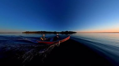 Akşam Huron Gölü 'ndeki Manitoulin Adası' nda gün batımında tekne gezisi. Yaz güneşinin battığı iç gölde bir tekne ve insanların silueti görülüyor. Akşamları balıkçı teknesine binmek..