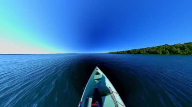 Gün batımında kara siluetiyle sakin suda süzülen tekne pruvası. Balık tutmak için en iyi zaman. Tekneden göl manzarası. Akşam eğlencesinin sinematik görüntüsü.