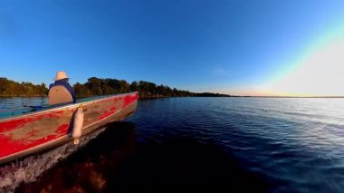 Huron Gölü 'ndeki Manitoulin Adası' nda akşam teknesi. Yaz günbatımında iç gölde bir tekne ve kadın manzarası. Akşamki balık oyunundan sonra balıkçı teknesine binmek..