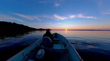 Huron Gölü 'ndeki Manitoulin adasında göl üzerinde gün batımı. Balıkçı turistlerle balıkçı teknesi işletmenin güzel manzarası. Seyahat anlarının sakin sahnesi ve balık oyunu sırasındaki macera.
