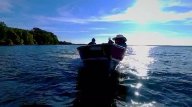 Kadın önde otururken adam levrek sürüyor. Güç sporu, iki kişilik bir balıkçı teknesi. Erkek ve kadın küçük v-gövdesi teknesinde balık tutarken tekneyle geziyorlar..