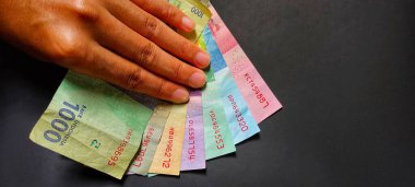 Rupiah banknotu siyah arka planda izole edilmiş, fotoğraf üst açıdan çekilmiş.