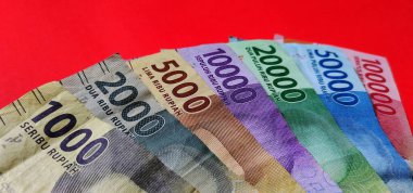 Endonezya 1000, 2000, 5000, 10000, 20000, 50000, 100.000 rupiah banknotları kırmızı arka planda izole edilmiştir..