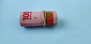 Bir rulo Endonezya 100 bin rupi banknot açık mavi arka planda izole.