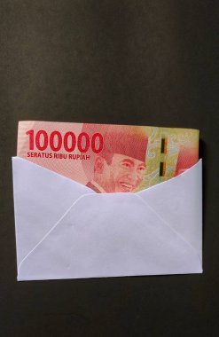 Siyah arka planda izole edilmiş beyaz zarf içinde Endonezya 100 bin rupia banknotu.