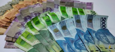 Stack of Indonesian banknotes of various denominations and colors worth 1000, 2000, 5000, 10000, 20000 and 50000, isolated on white background.
