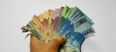 Various colors and denominations of Indonesian rupiah currency in hand isolated white background