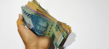 Various colors and denominations of Indonesian rupiah currency in hand isolated white background