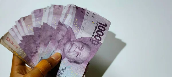 10,000 rupiah banknote in hand. Business concept illustration, isolated white background.