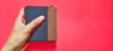 Kırmızı arka planda bir erkek cüzdanı tutan adam..