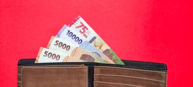 Top view of a wallet containing new Indonesian banknotes issued in 2022. Rupiah currency concept isolated on red background