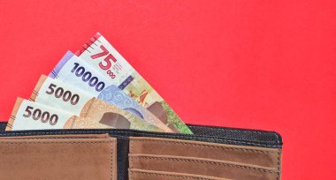 Top view of a wallet containing new Indonesian banknotes issued in 2022. Rupiah currency concept isolated on red background. Negative space
