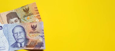 New Indonesian rupiah banknotes issued in 2022. Rupiah currency concept isolated on a yellow background and negative space.