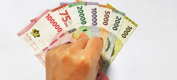 Elinde yeni çıkarılmış Endonezya banknotları tutan adam. Rupiah para birimi kavramı beyaz arka planda izole edildi. Üst görünüm