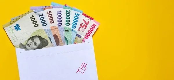 2022 'de 1000 Rupi' den 100.000 Rupi 'ye yeni banknotlar yayınlandı. Üzerinde THR yazan beyaz bir zarf olan Endonezya rupia parası. Tunjangan Hari Raya kavramı sarı arka planda izole edildi. Negatif boşluk