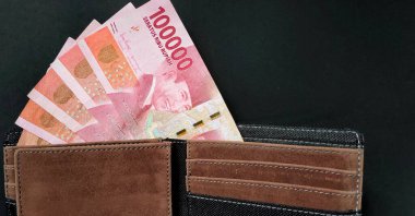 İçinde Endonezya banknotları olan bir cüzdanın üst görüntüsü. Rupiah para birimi kavramı siyah arkaplanda izole edildi.
