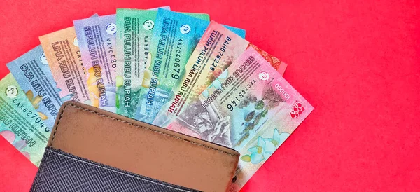 Bir cüzdanın üst görüntüsü ve 2022 'de yayınlanan yeni Endonezya rupia banknotları. Kırmızı arkaplanda izole edilmiş rupiah para birimi kavramı